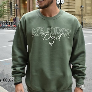 May include: A green sweatshirt with the text "Air Force Dad" in white lettering. The sweatshirt has a white Air Force logo.