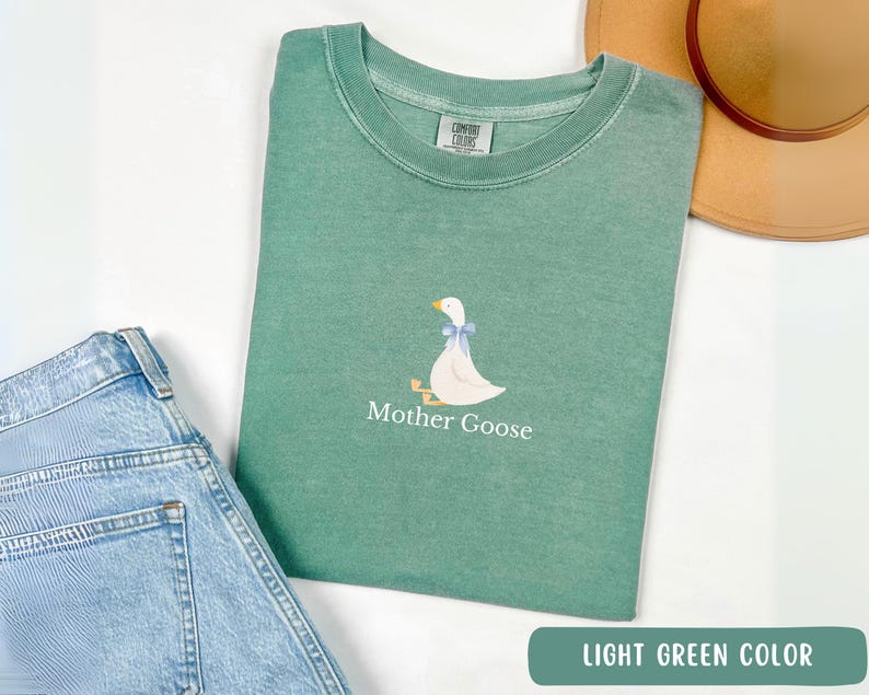 May include: A light green t-shirt with a white goose illustration and the text "Mother Goose" printed on the front.