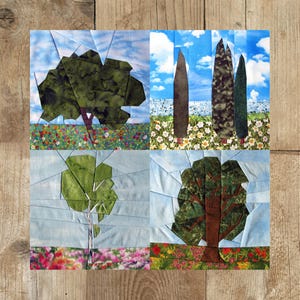 Könnte beinhalten: Eine Collage aus vier Stoffquadraten, die verschiedene Bäume darstellen. Das obere linke Quadrat zeigt einen grünen Baum mit einem braunen Stamm vor einem blauen Himmel mit weißen Wolken. Das obere rechte Quadrat zeigt drei hohe, dünne, grüne Bäume vor einem blauen Himmel mit weißen Wolken. Das untere linke Quadrat zeigt einen grünen Baum mit einem weißen Stamm vor einem blauen Himmel mit weißen Wolken. Das untere rechte Quadrat zeigt einen grünen Baum mit einem braunen Stamm vor einem blauen Himmel mit weißen Wolken.