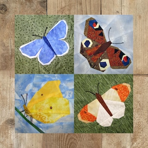 May include: A patchwork quilt block featuring four different butterfly designs. The top left butterfly is blue, the top right butterfly is brown with black and blue accents, the bottom left butterfly is yellow, and the bottom right butterfly is white with orange accents.