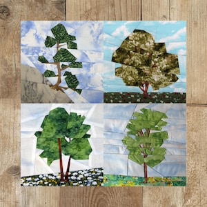 Könnte beinhalten: Eine Collage aus vier Papier-Patchwork-Blöcken, die jeweils einen Baum in einer anderen Jahreszeit darstellen. Der Block oben links zeigt eine Kiefer im Winter mit einem schneebedeckten Hintergrund. Der Block oben rechts zeigt einen Laubbäume im Frühling mit einem grünen Hintergrund und rosa Blüten. Der Block unten links zeigt einen Laubbäume im Sommer mit einem grünen Hintergrund und weißen Blüten. Der Block unten rechts zeigt einen Laubbäume im Herbst mit einem gelben und orangefarbenen Hintergrund.