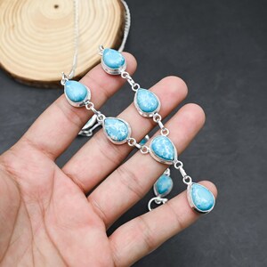 Peut inclure: Un ensemble collier et boucles d'oreilles en argent avec des pierres bleues claires en forme de goutte d'eau et des marbrures blanches. Les pierres sont serties dans des lunettes en argent et reli&eacute;es par des maillons en argent.