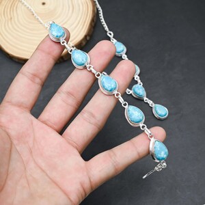 Peut inclure: Un ensemble collier et bracelet en argent orn&eacute; de pierres bleues claires en forme de goutte. Les pierres sont serties dans des montures en argent et reli&eacute;es par des cha&icirc;nes en argent. Les bijoux sont pr&eacute;sent&eacute;s sur une surface sombre.