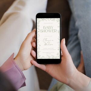 K&ouml;nnte beinhalten: Ein Smartphone, auf dem eine Babyparty-Einladung mit floralem Rand angezeigt wird. Die Einladung lautet "Baby Shower" und "Honoring  Clarence Walton".