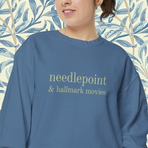 May include: A blue sweatshirt with the text "needlepoint & hallmark movies" in light green.