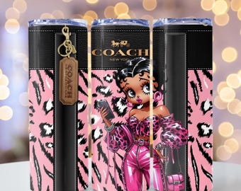 May include: A pink and black leopard print tumbler with a black leather strap and a gold keychain with the word "COACH" on it. The tumbler features a cartoon image of a woman with pink and black clothing and a pink purse.