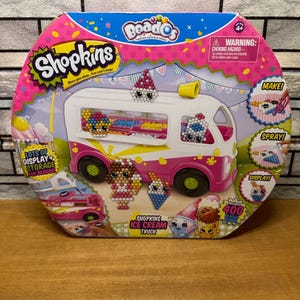 May include: A Shopkins Ice Cream Truck toy set in a colorful box. The box features a pink and blue design with the Shopkins logo and the text "Once you shop...you can't stop!" The set includes 400 beads.