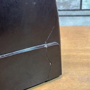 K&ouml;nnte beinhalten: Ein schwarzer Vintage-Plattenspieler mit einem Riss im Kunststoffgeh&auml;use.