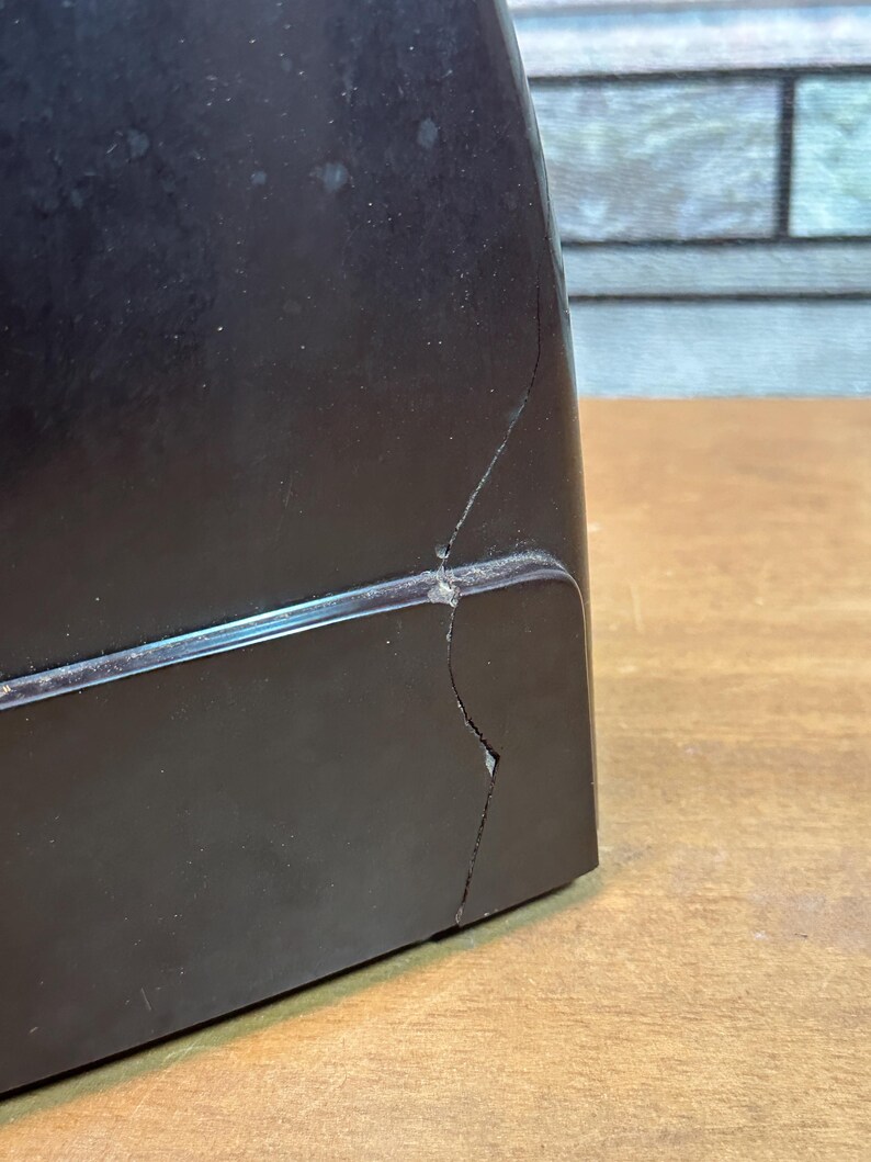 K&ouml;nnte beinhalten: Ein schwarzer Vintage-Plattenspieler mit einem Riss im Kunststoffgeh&auml;use.