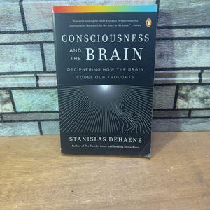 May include: A black and white book titled "Consciousness and the Brain: Deciphering How the Brain Codes Our Thoughts" by Stanislas Dehaene. The book cover features a white light radiating from the center of a black background.