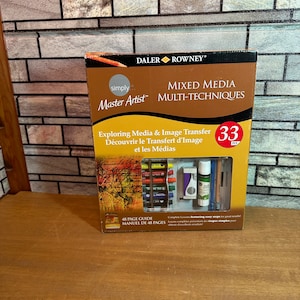 May include: A Daler Rowney Simply Master Artist Mixed Media Multi-Techniques art set with 33 pieces. The set includes pastels, pencils, a glue stick, an eraser, and a 48-page guide. The box is brown with a vintage-style image on the front.