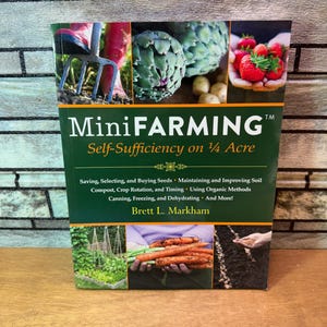 May include: A book titled "MiniFARMING" with the subtitle "Self-Sufficiency on 1/4 Acre." The cover features images of gardening tools, artichokes, strawberries, and carrots. The book's topics include saving seeds, crop rotation, and organic methods.