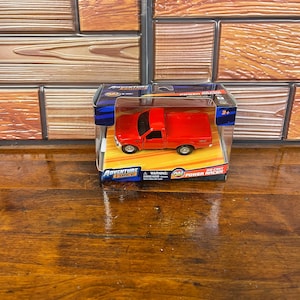 May include: A red die-cast pickup truck toy inside its original packaging box. The box features the Adventure Force logo, the text Power Racer, a pull-back action label, and a warning about small parts for children under 3 years of age.