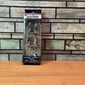 May include: A Harry Potter miniature figure set in a clear plastic display case. The figures are of various characters from the Harry Potter series. The packaging includes the Harry Potter logo and character names.