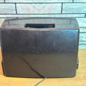 K&ouml;nnte beinhalten: Ein dunkelbraunes Vintage-Radio mit rechteckiger Form und einer kleinen rechteckigen &Ouml;ffnung oben.