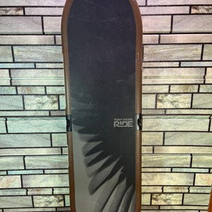 May include: A brown and black Tony Hawk Ride skateboard controller featuring a textured black grip surface with a dark gray wing graphic and the text Tony Hawk Ride printed in white on the center of the board deck.