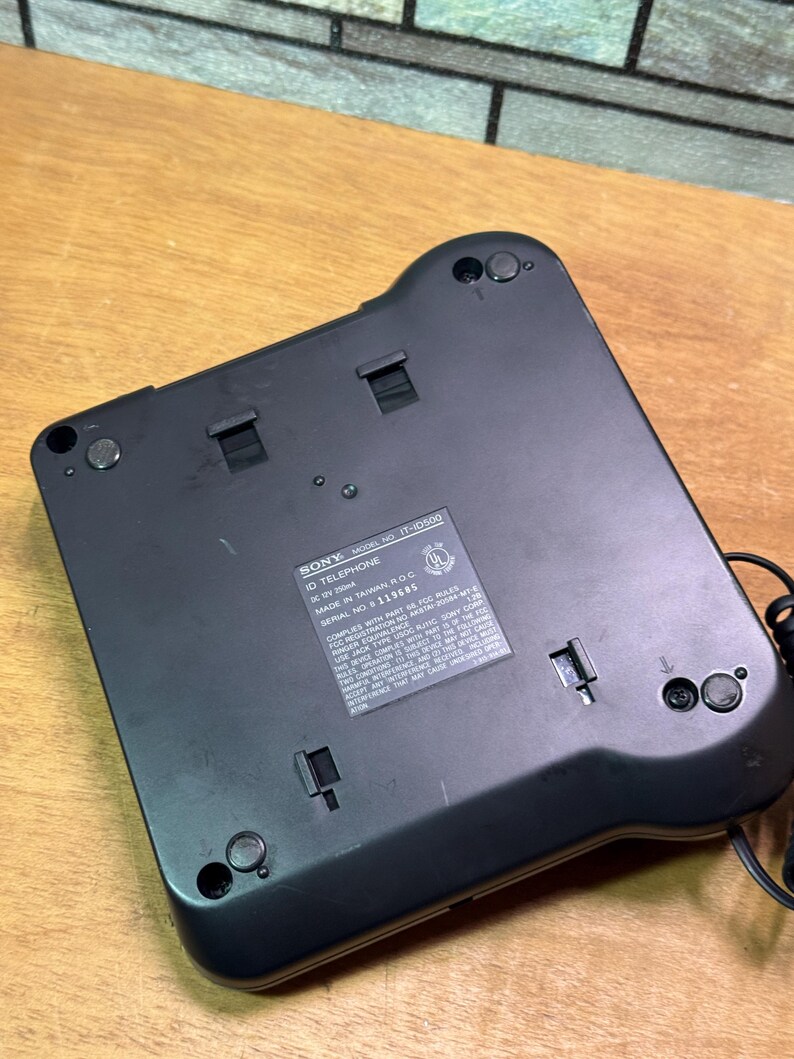 Puede incluir: Un tel&eacute;fono ID Sony negro, modelo IT-10500, con una etiqueta que incluye el texto "MADE IN TAIWAN R.O.C." y "SERIAL NO. 119685." El tel&eacute;fono tiene forma rectangular con esquinas redondeadas y varios botones y puertos peque&ntilde;os.