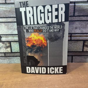 May include: A book titled "The Trigger: The Lie That Changed The World - Who Really Did It And Why" by David Icke. The cover features a black and white photo of the World Trade Center towers with smoke and flames.
