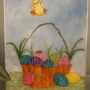 Peut inclure: Un poussin jaune aux pattes orange vole au-dessus d'un panier rempli d'œufs de Pâques colorés. Le panier est en matériau orange tissé et a une poignée en corde brune. L'arrière-plan est un ciel bleu clair avec des nuages blancs.