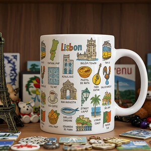 May include: White ceramic mug with a colorful illustration of Lisbon, Portugal. The mug features various landmarks, symbols, and text related to the city, including the Belem Tower, Pastel de Nata, Fado guitar, and the phrase "Lisbon" in bold letters.