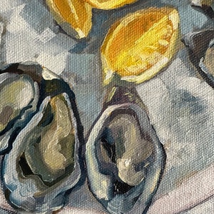 May include: A close-up of a white plate with several oysters and lemon slices. The oysters are open and show their pearly interiors. The lemon slices are yellow and juicy.