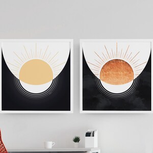 Peut inclure: Deux impressions encadrées avec un fond noir et un soleil stylisé avec des rayons au centre. Le soleil de l'impression de gauche est jaune et le soleil de l'impression de droite est cuivre.