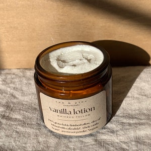 Puede incluir: Un tarro de vidrio marr&oacute;n con una etiqueta blanca que dice "Sun & Pine Essentials Vanilla Lotion Whipped Tallow 100% grass fed & finished tallow, olive oil infused with calendula, whole vanilla beans, arrowroot powder, organic"