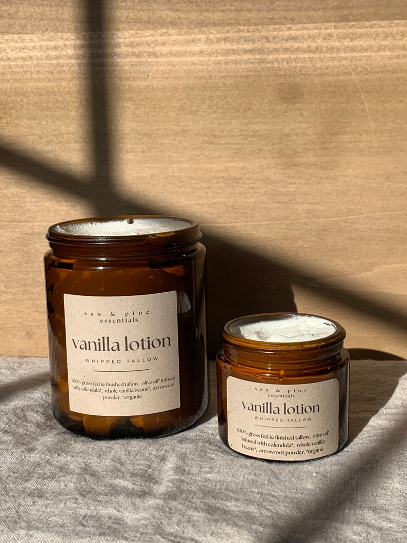 Puede incluir: Dos frascos de vidrio &aacute;mbar de loci&oacute;n de vainilla con etiquetas blancas. Las etiquetas dicen "sun & pine essentials" y "vanilla lotion whipped tallow". El texto en las etiquetas describe los ingredientes, que incluyen sebo alimentado con pasto, aceite de oliva, cal&eacute;ndula, granos de vainilla enteros y polvo de ra&iacute;z de flecha.