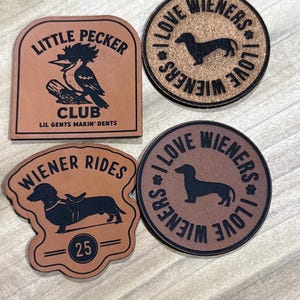 May include: Four brown leather patches with black text and illustrations. One patch reads "LITTLE PECKER CLUB" with a bird illustration. Two patches say "I LOVE WIENERS" with a dachshund silhouette. The last patch says "WIENER RIDES 25".