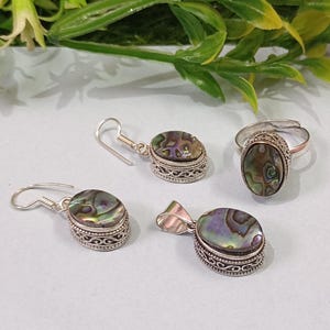 Peut inclure: Un ensemble de bijoux en argent avec des incrustations de nacre d'ormeau. L'ensemble comprend une bague, un pendentif et une paire de boucles d'oreilles.