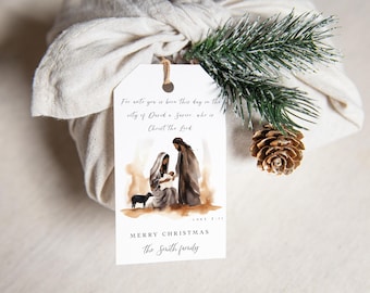 May include: A white gift tag with a watercolor illustration of the nativity scene. The text on the tag reads "For unto you is born this day in the city of David a Savior, who is Christ the Lord." Below the illustration, it says "Merry Christmas" and "The Smith family".