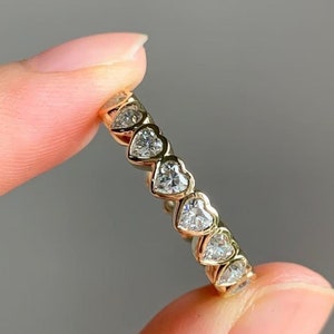 以下が含まれることがあります： ハート型のダイヤモンドが並んだゴールドのバンドリングです。