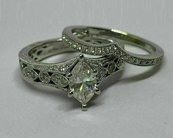 May include: A silver engagement ring set with a marquise-shaped diamond and a matching band with pave diamonds.