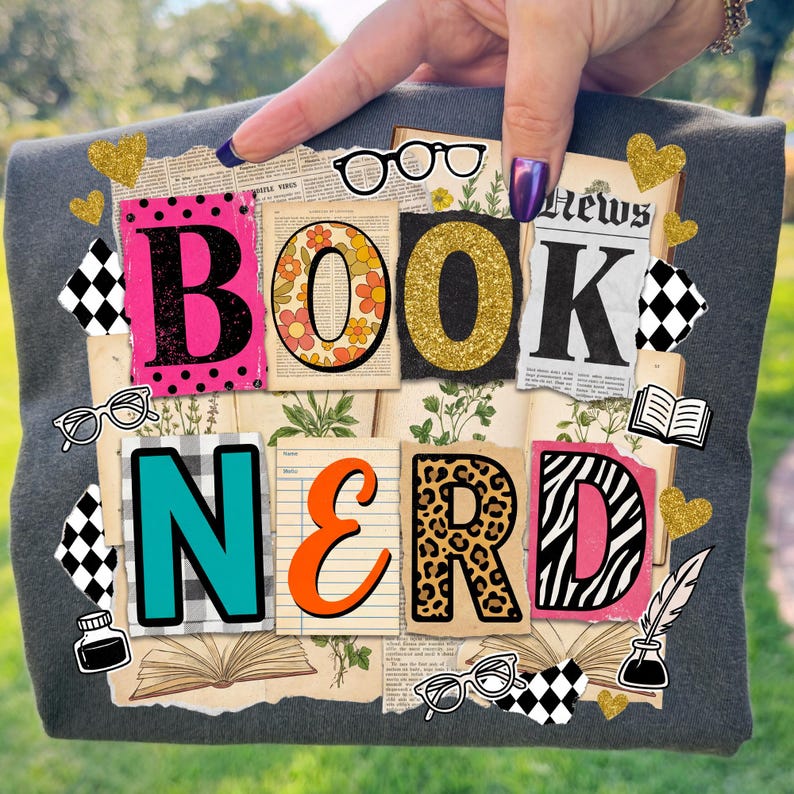 May include: Grey t-shirt featuring the words "BOOK NERD" in a collage design. The letters are in diverse colours and patterns, such as pink polka dots, floral, gold glitter, and leopard print. Decorative elements include glasses, hearts, and book illustrations.