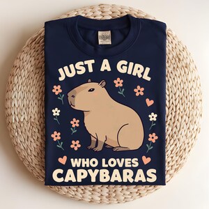 May include: A navy blue t-shirt with a graphic of a capybara and the text "Just a girl who loves capybaras".