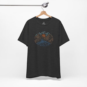 May include: A dark heather grey t-shirt with a graphic of a mountain range with a sun setting behind it. The graphic is in shades of brown, blue, and orange.