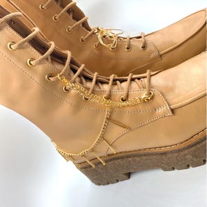 Close-up of a gold-plated charm chain with gold beads detail on boots.