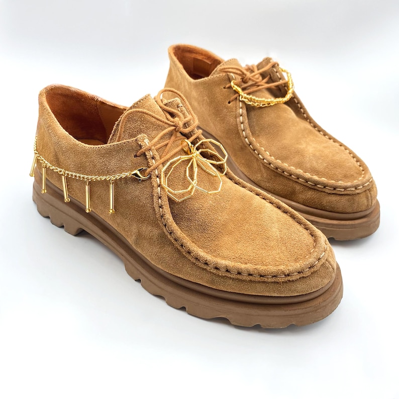 Gold shoelace charm on a gold chain, enhancing the look of casual footwear.