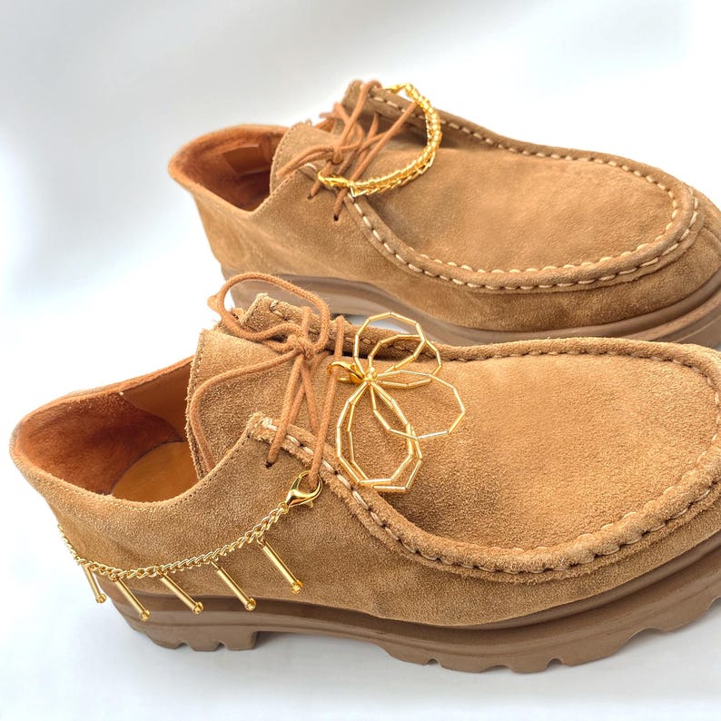 Elegant gold charm chain on boots, combining beads and floral elements for style.