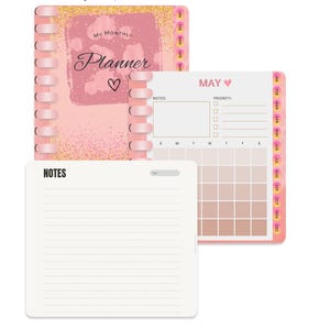 Puede incluir: Una agenda rosa y dorada con un calendario mensual y una sección de notas. La portada presenta el texto "My Monthly Planner" con un corazón. El calendario es para el mes de mayo e incluye una sección de prioridades.