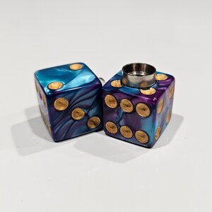 May include: Two purple and blue dice with gold dots. One die has a silver top.