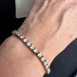 May include: A gold tennis bracelet with round clear stones.
