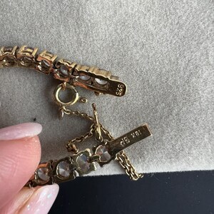 May include: A gold bracelet with clear stones and a clasp that reads "18K 585".