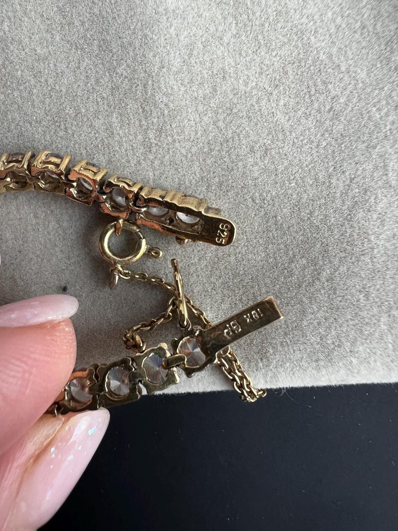 May include: A gold bracelet with clear stones and a clasp that reads "18K 585".
