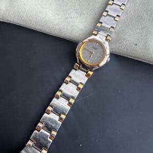 May include: A silver and gold two-tone Citizen Quartz watch with a silver face and gold hands.