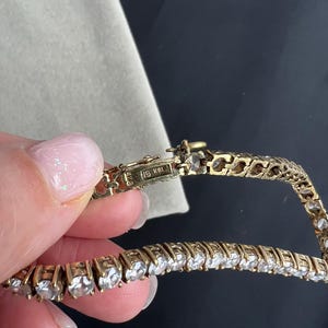 May include: A gold chain bracelet with small round clear stones. The clasp has the inscription "14K 585".