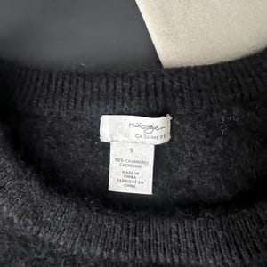 May include: Close-up of a black cashmere sweater. The tag reads "Halogen CASHMERE" and "100% CASHMERE/ CACHEMIRE". The tag also indicates the sweater is size "S" and "MADE IN CHINA / FABRIQU&Eacute; EN CHINE".