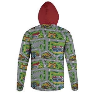May include: A hooded sweatshirt with a cityscape pattern. The design features roads, buildings, and green spaces in a playful layout. The hood is a solid maroon color, contrasting with the gray, green, yellow, and red pattern on the body.