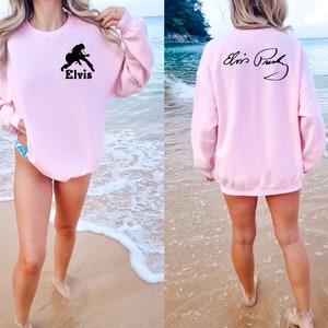 May include: Pink sweatshirt with a black silhouette of Elvis Presley playing a guitar on the front and his signature on the back.