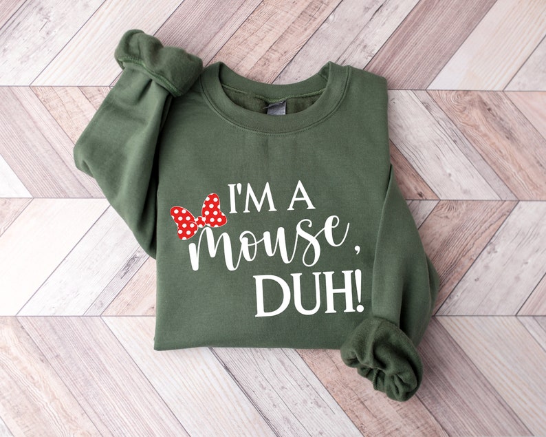 May include: A green sweatshirt with a white graphic that says "I'm a mouse, DUH!" and a red bow with white polka dots.